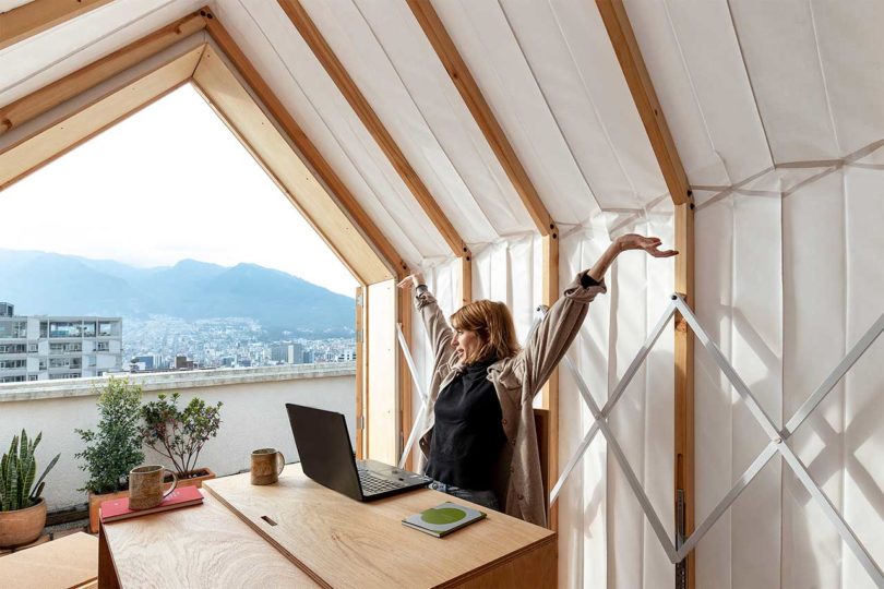 angled interior view of expandable living structure with woman sitting at table with laptop