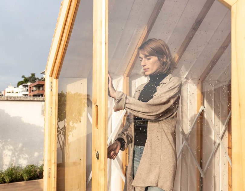 closeup angled view looking through window of expandable shelter with woman inside locking door