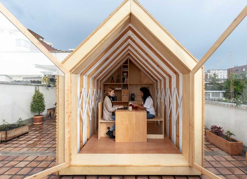 exterior view of expandable shelter looking inside with two women sitting at table