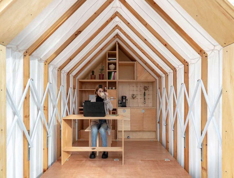 view inside expandable living shelter with woman sitting at desk working