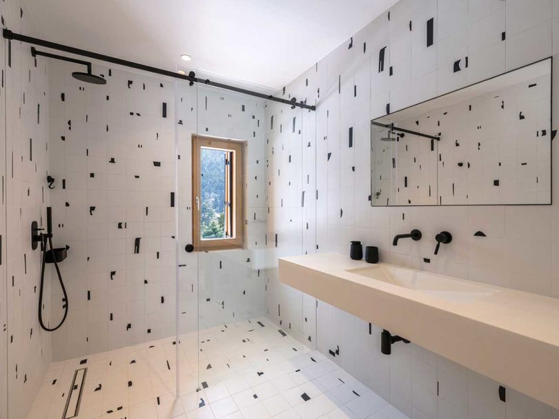 angled view of modern bathroom with white tile with random black shapes