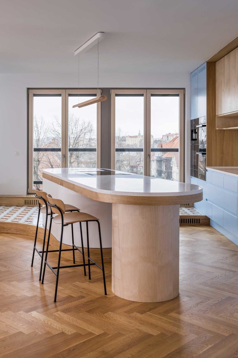 side interior view of modern kitchen with oval island and blue cabinets