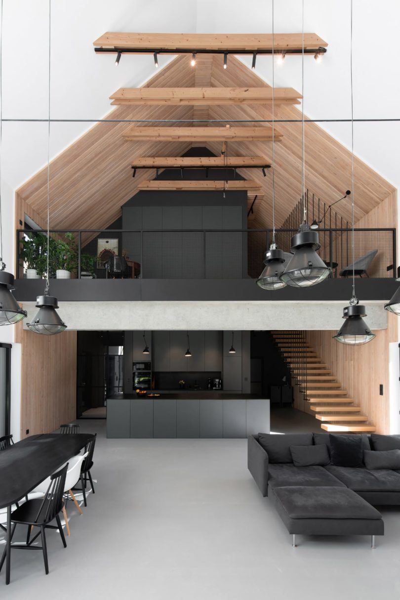 interior view of modern double height living space with black kitchen and loft space above