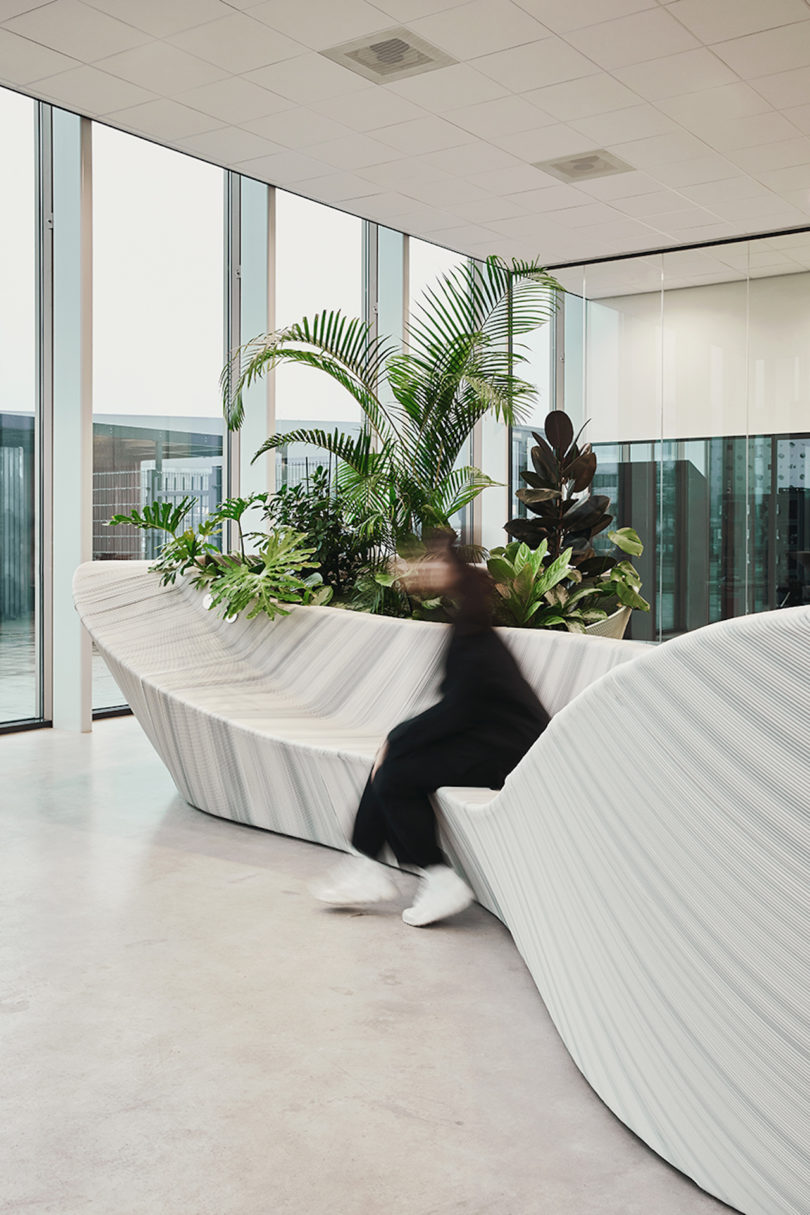 woman sitting on sculptural, white and grey furniture in office lobby