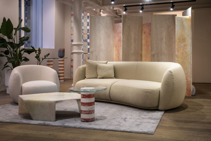 showroom with ivory sofa and armchair sitting in front of suspended panels of stone material