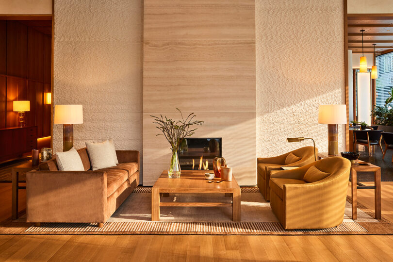 well-lit lobby styled space with a brown sofa, two brown armchairs, a square brown coffee table, and a fireplace