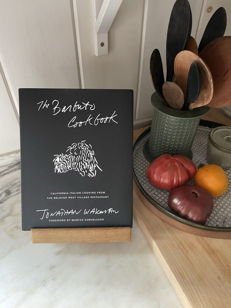 kitchen counter with product, cooking utensils, and a cookbook on a wooden stand