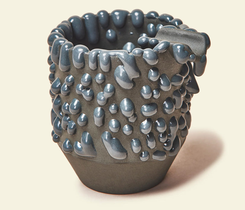 Grey ceramic cup-style ashtray finished with bumpy globular glaze finish.