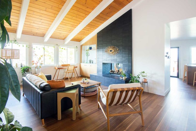 angled interior view of modern living room with angled wood beam ceiling and black tile fire place