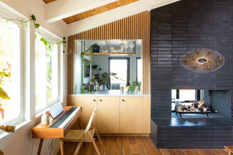 edge view of modern living room with built-in cabinetry and black tiled fireplace