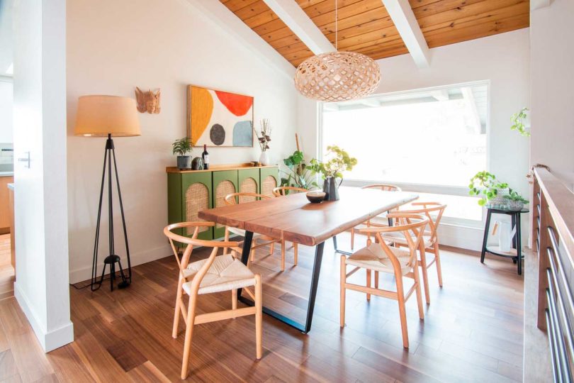 angled interior view of modern midcentury dining room with angled ceiling and wishbone chairs