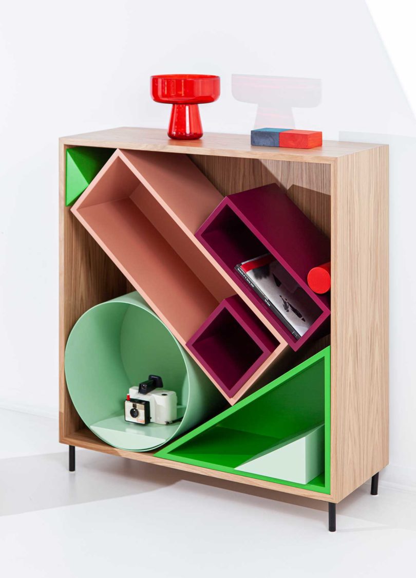 angled view of modular storage shelf with colorful geometric boxes inside with red lamp on top