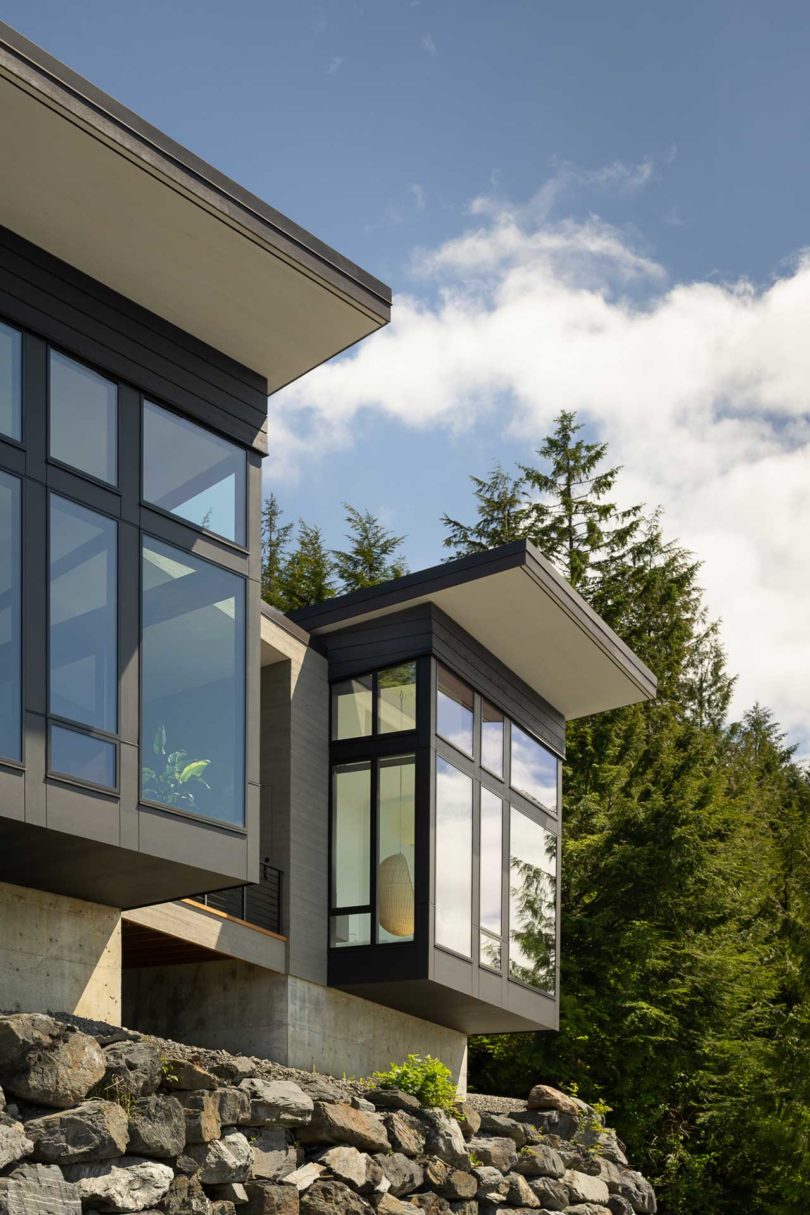 exterior view of modern house atop stacked rocks above water