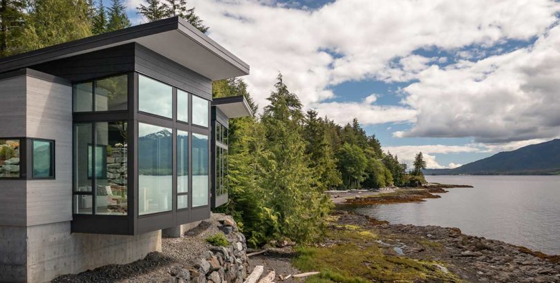 exterior side view of modern house atop stacked rocks above water