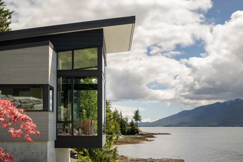 exterior side view of modern house atop stacked rocks above water