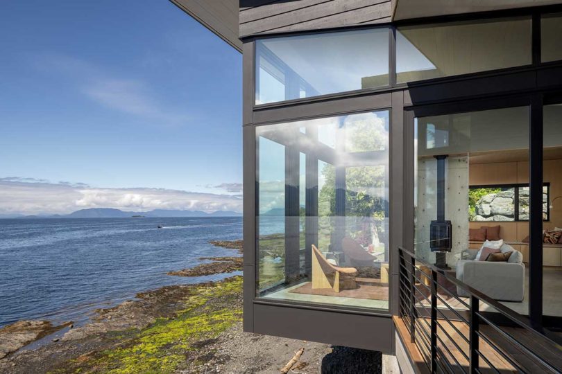 exterior side view of modern house atop stacked rocks above water