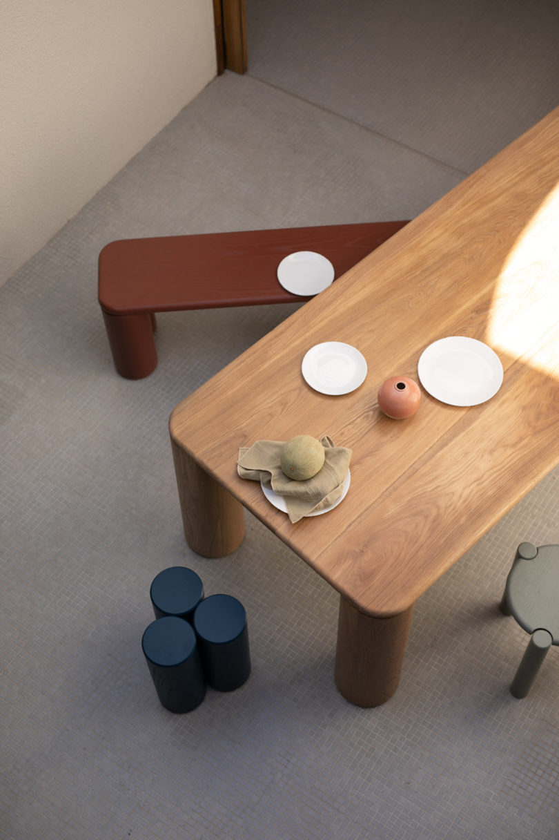 brown dining table with maroon bench and blue side table