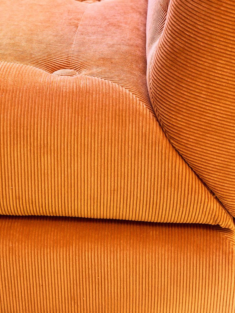 corner section of orange corduroy chair