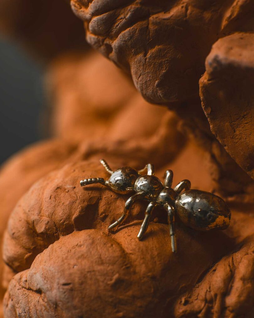 closeup view of terracotta floral chair sculpture with brass bug