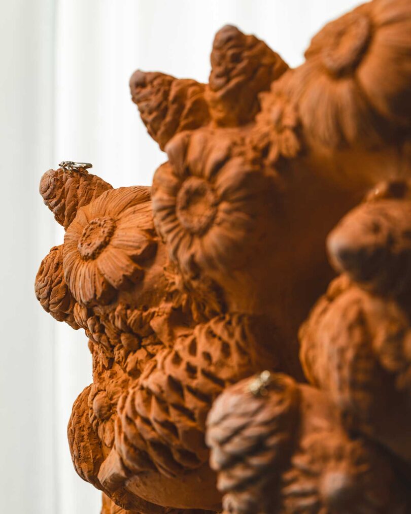 closeup view of terracotta floral chair sculpture with brass bug