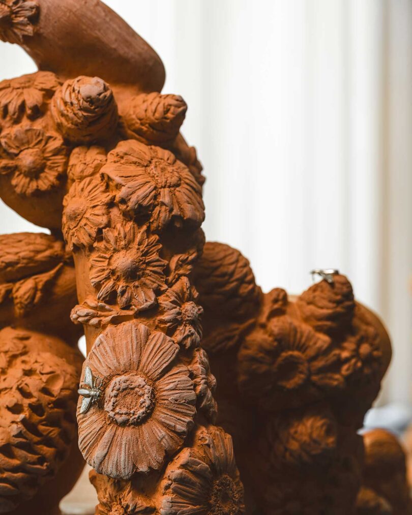 closeup view of terracotta floral chair sculpture with brass bug