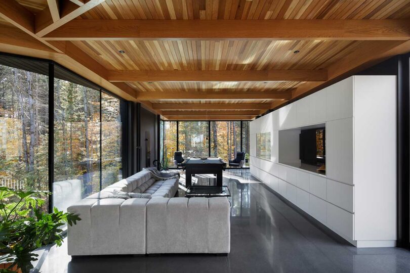 interior view of modern living room with modular sofa, white builtins and wood ceiling