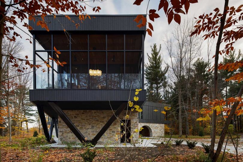 end view of exterior view of modern house with stone ground level and wood and glass upper level