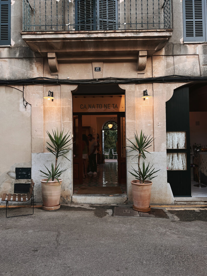 exterior of an old building with a large wooden door and planters on either side