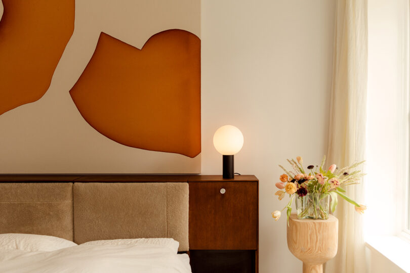 styled bedroom with round table lamp sitting on the nightstand/headboard