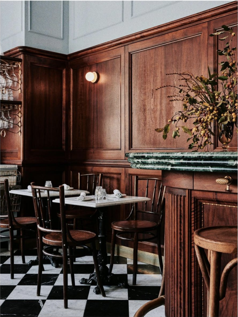 dark wood cafe interior with tables, chairs, and a black and white floor