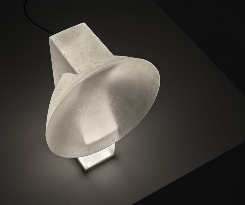 Overhead angled view of Vestige lamp glowing on table in darkened room.