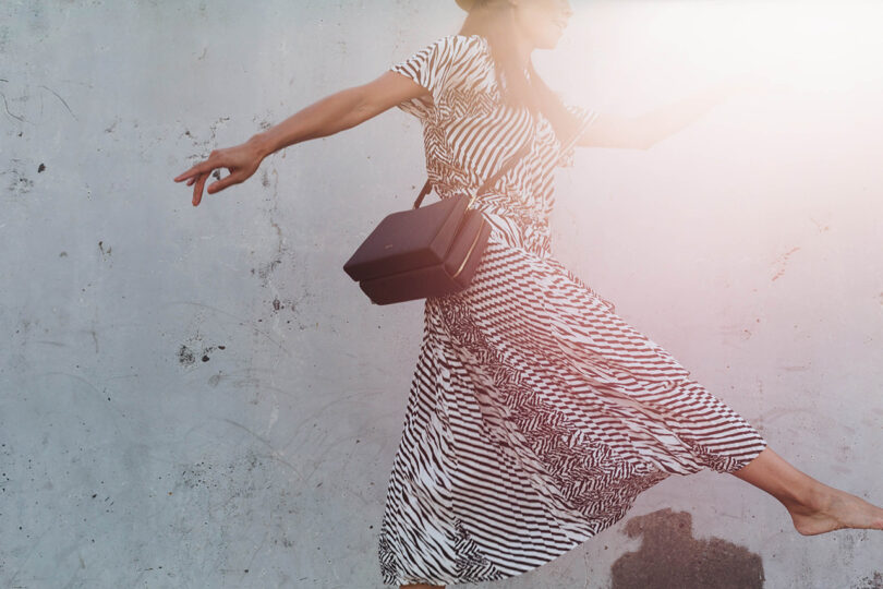 light-skinned person wearing a black and white garment while carrying a black bag