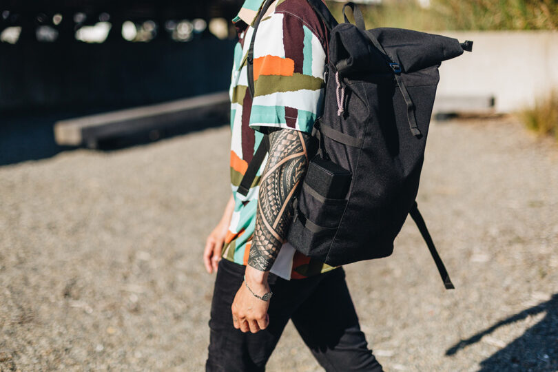 light-skinned person wearing a bold geometric short-sleeved shirt and carrying a black backpack