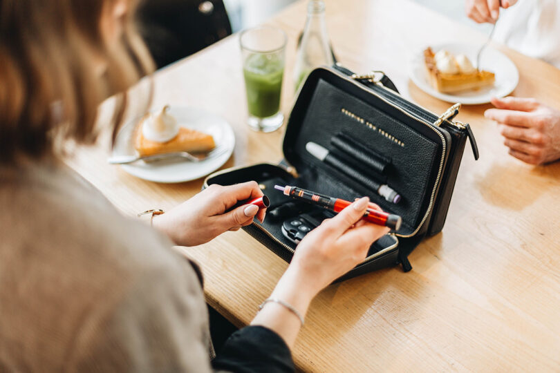 light-skinned hands interacting with diabetes tools in a black bag on a table