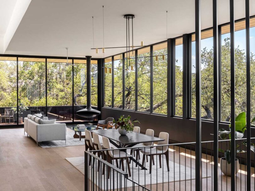 angled interior view of modern home dining room and living room surrounded by windows