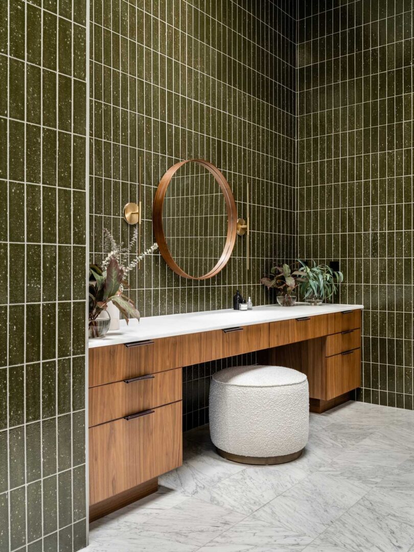 angled interior view of modern bathroom with dark green tile and wood cabinets