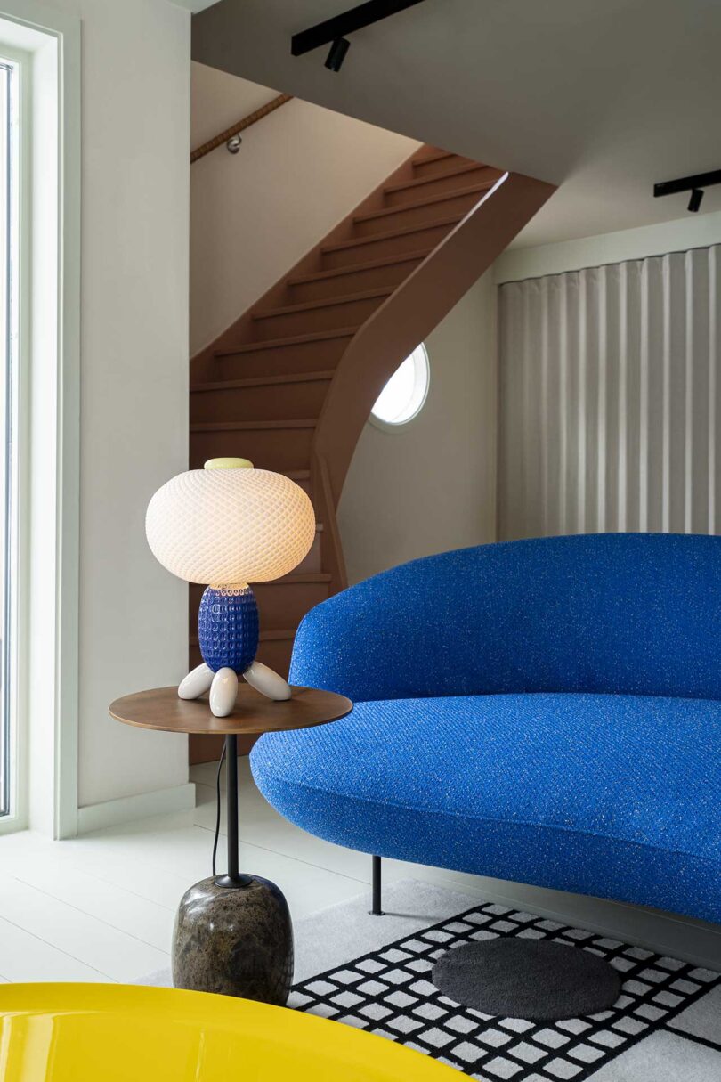 interior view showing partial blue sofa with pedestal table with unique glass lamp