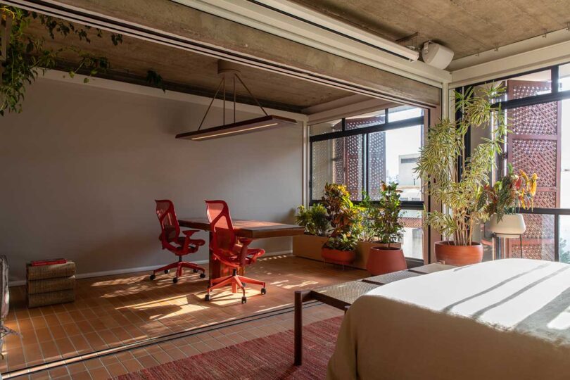 angled view from bedroom into modern home office with 2 red chairs