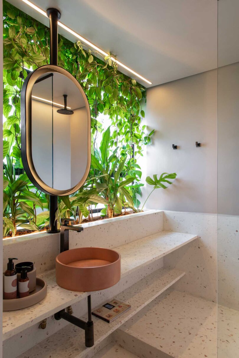 angled view of modern bathroom with suspended mirror with plants behind it