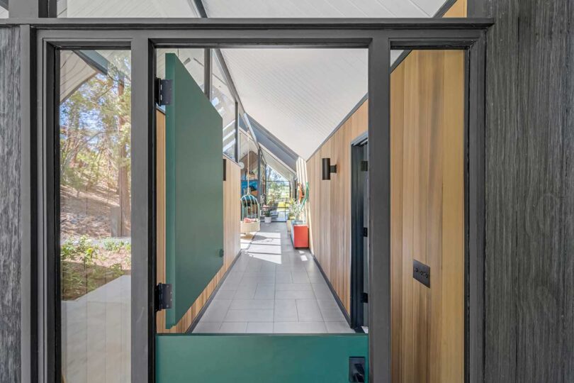 closeup of green front door with top part open looking down hallway of modern house