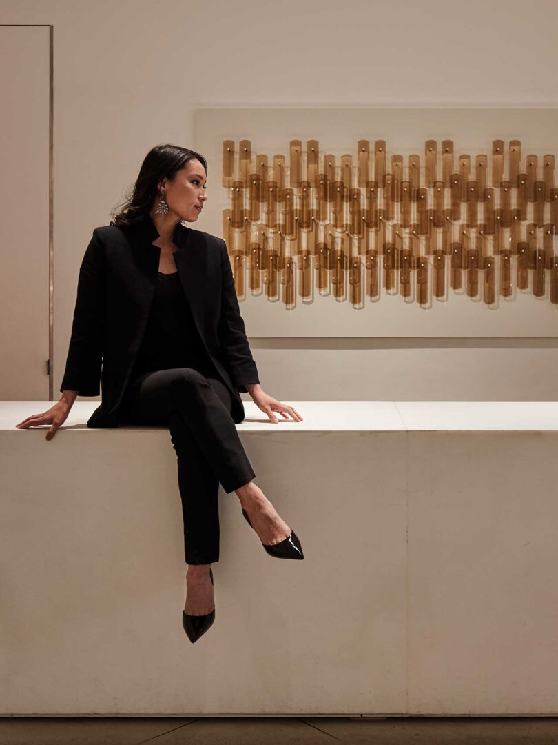 Woman sitting on bend in front of art on wall