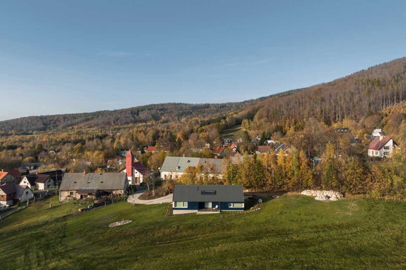 elevated view of modern blue cabin with hill behind