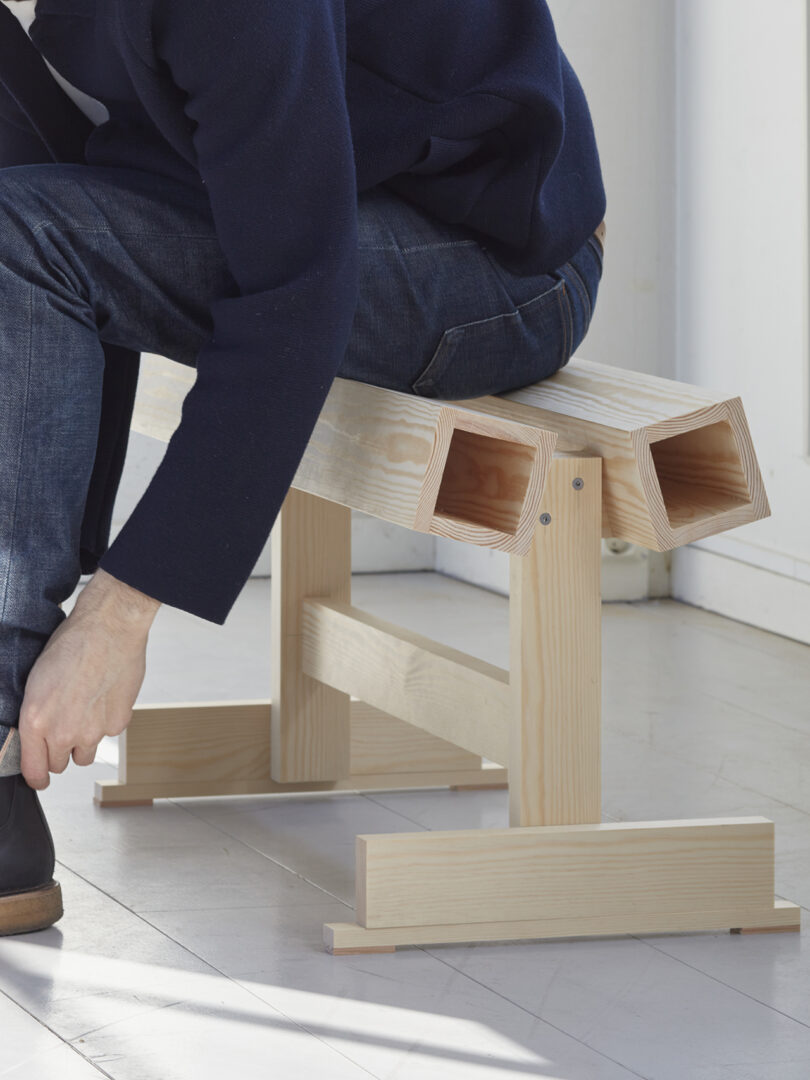 person sitting on light wood bench prototype