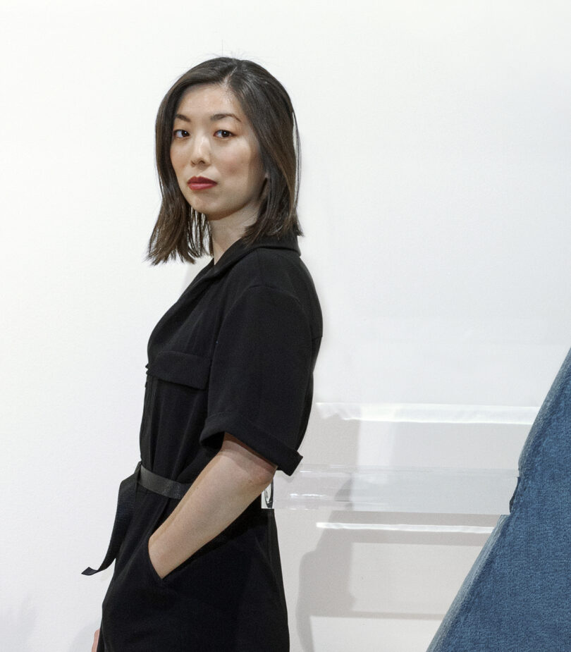 light-skinned woman with dark shoulder length hair wearing a black outfit and looking into the camera