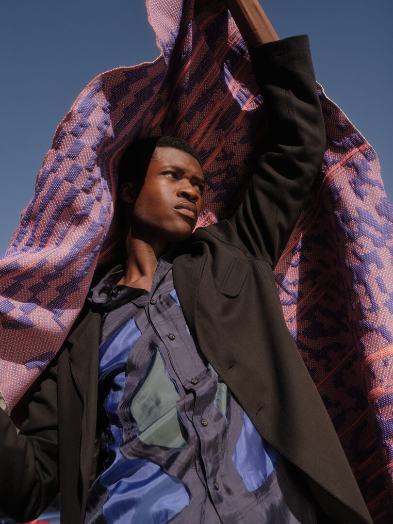 brown-skinned man with glasses holds a blanket over his head