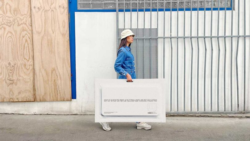 woman in white hate walking down road carrying large white envelope