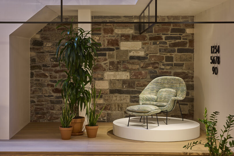 upholstered armchair with ottoman on a white pedestal in a showroom