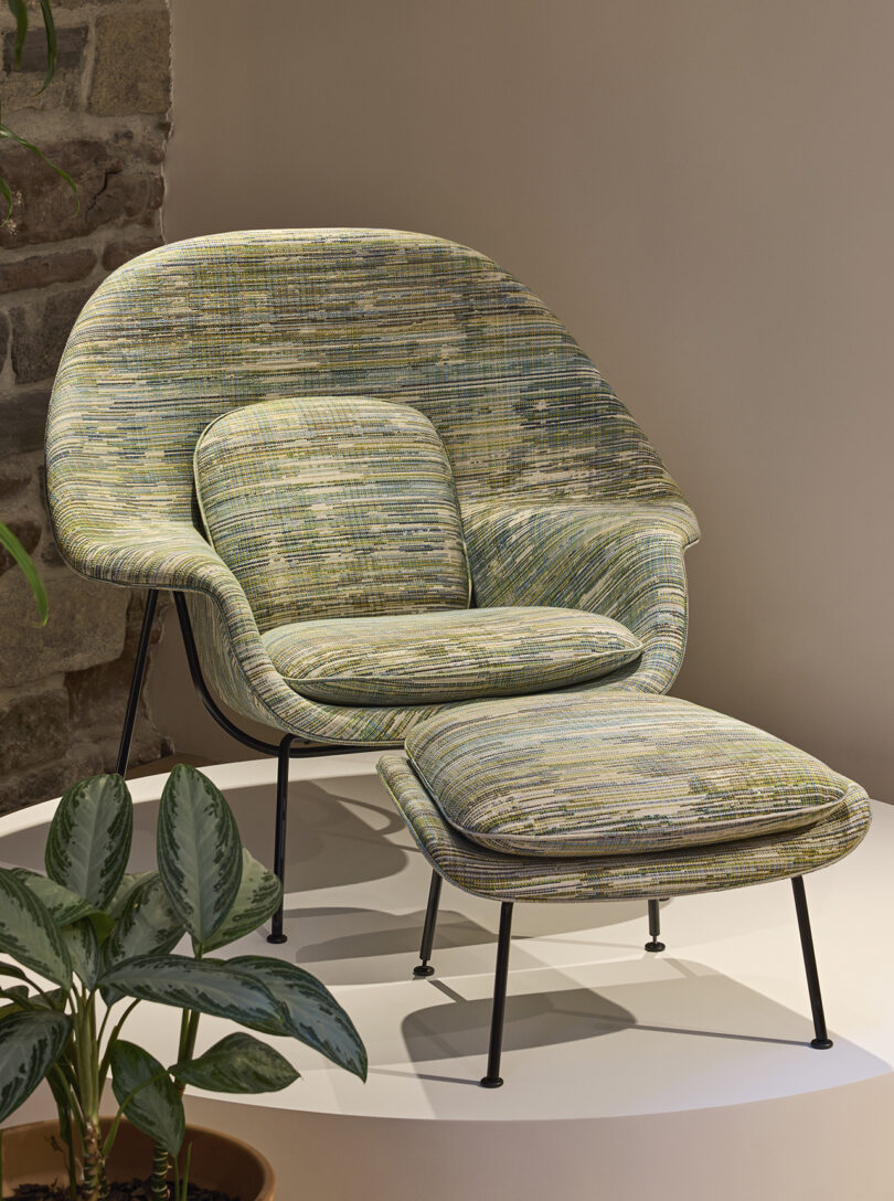 upholstered armchair with ottoman on a white pedestal in a showroom