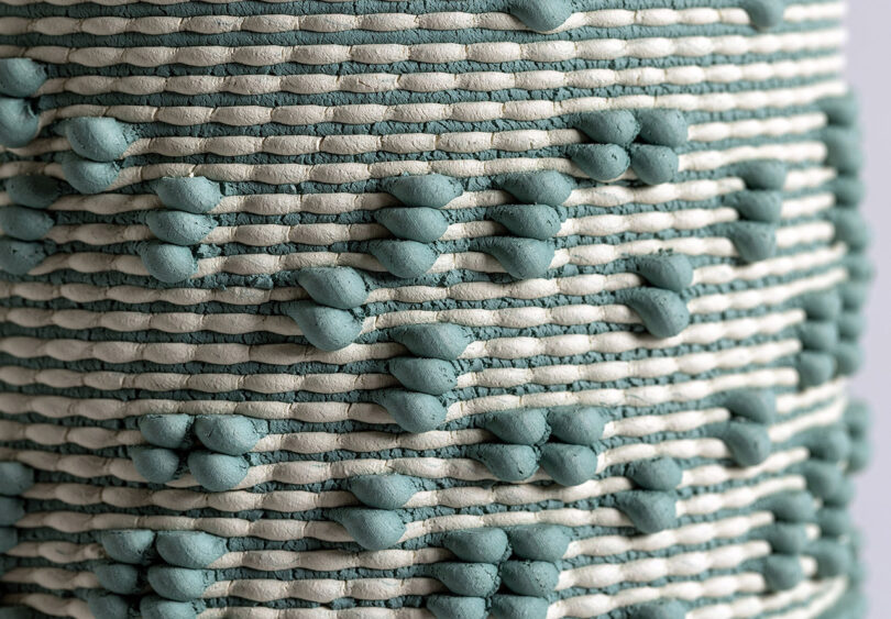 Closeup of green and natural clay hued Dyadic Series dual extrusion 3D printed ceramic sculptures, showcasing their woven-like patterns and textures created by 3D printing with two clay colors simultaneously. 