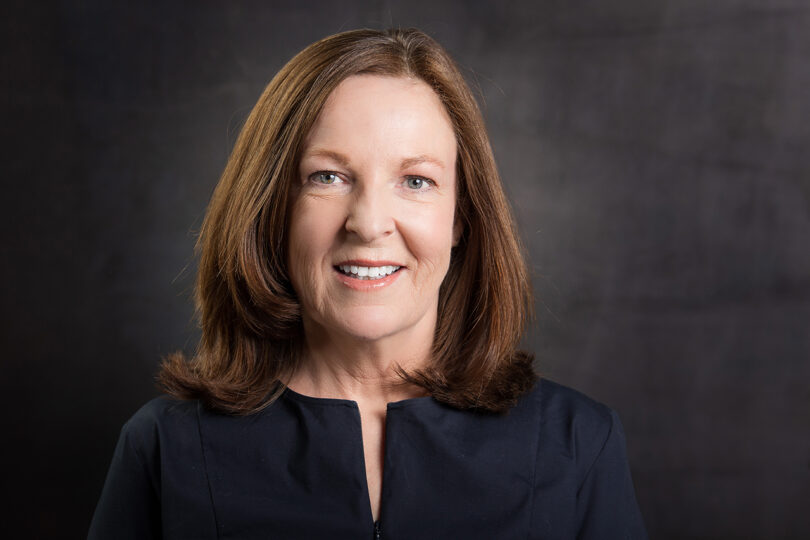 light-skinned woman with medium length brown hair wearing a black shirt